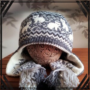 May include: A gray and white knitted winter hat with ear flaps and a pom-pom. The hat has a geometric pattern and is made of a soft, warm material.