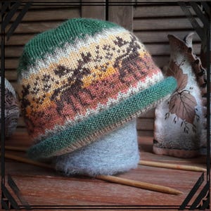 May include: A green, brown, and cream knitted hat with a geometric pattern. The hat is sitting on a gray yarn ball.
