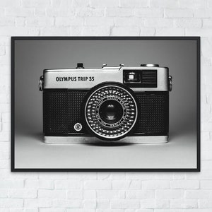 Op de afbeelding: Een zwart-zilveren Olympus Trip 35 filmcamera op een zwarte achtergrond.