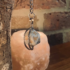 May include: A silver keychain with a white and gold dice charm. The dice is in a cage-like holder.