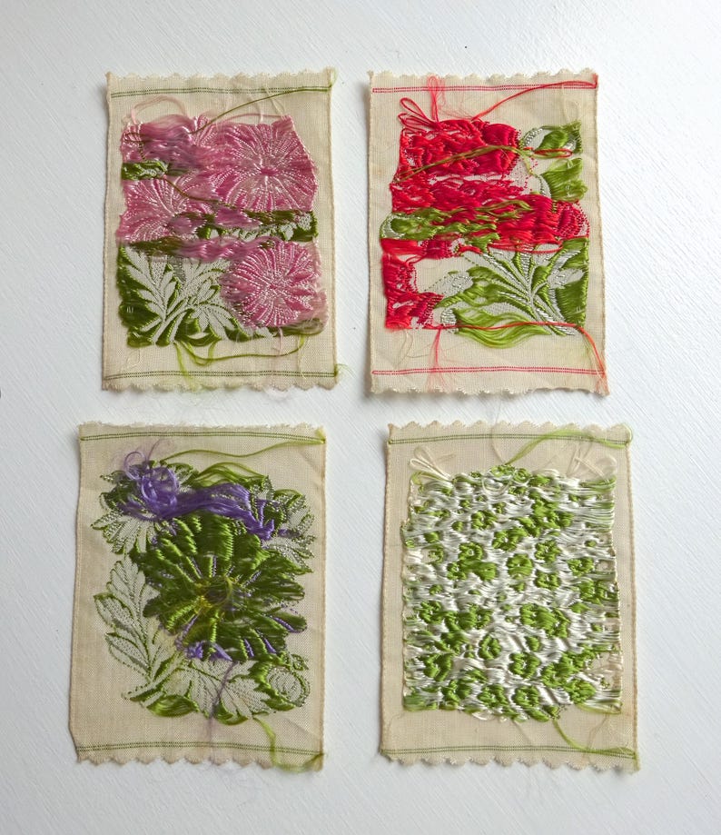 以下が含まれることがあります： 花柄の刺繍が施された小さな布の正方形が4つ。正方形はピンク、赤、緑、紫の色合いです。