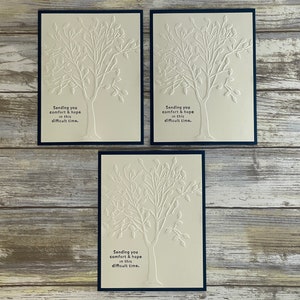 May include: Three white cards with black borders, each featuring a white embossed tree design and the text "Sending you comfort & hope in this difficult time."