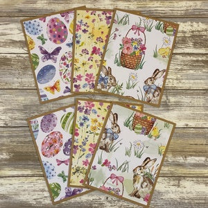 May include: Set of eight Easter-themed greeting cards featuring bunnies, eggs, flowers, and a basket. The cards have a watercolor-like style and are printed on a white background.