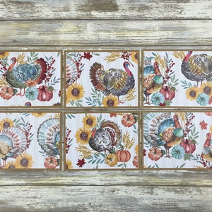 May include: Six brown and white cardstock place cards with a Thanksgiving theme. Each card features a watercolor illustration of a turkey with fall foliage, sunflowers, and pumpkins.