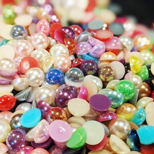 May include: A large assortment of colorful pearl-like beads in various shades of pink, blue, green, purple, and white. The beads are round and have a smooth, glossy finish.