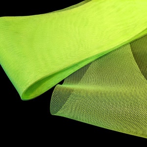 May include: A bright green tulle fabric with a fine mesh texture. The fabric is folded and draped, showcasing its soft and airy quality.
