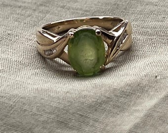 May include: A gold ring with a green oval gemstone and small diamonds set in the band.