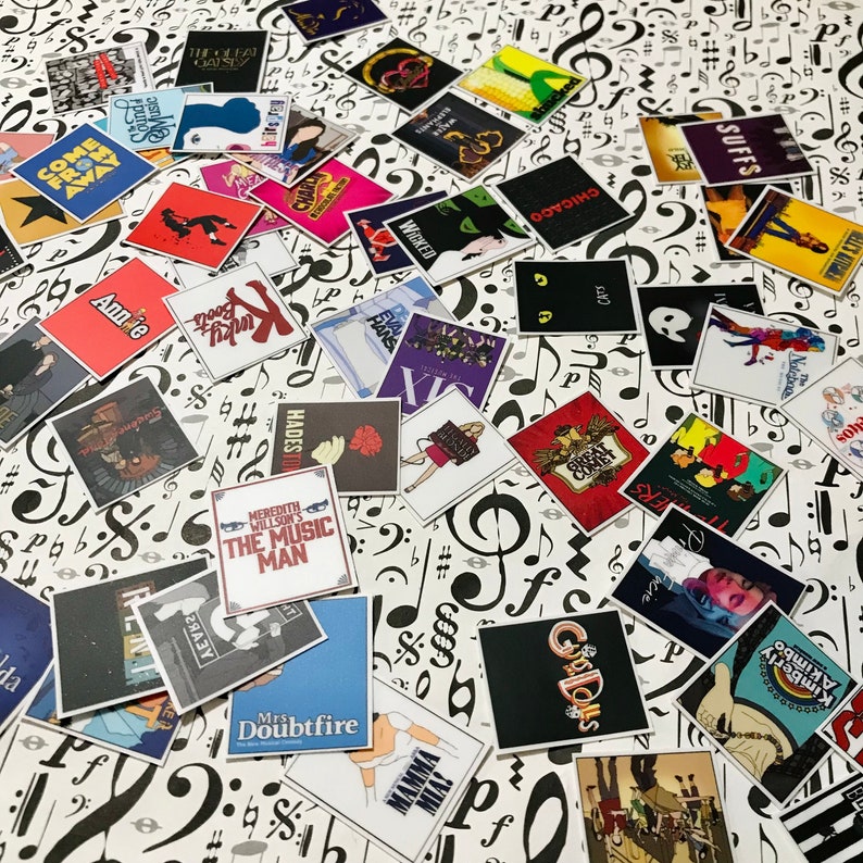 May include: A collection of colorful square stickers featuring the names of various Broadway musicals, including "Wicked", "Chicago", "Annie", "The Music Man", "Hadestown", "The Great Comet", "Suffs", "Kimberly Akimbo", "Mrs. Doubtfire", "Go-Go Dolls", and "Mamma Mia".