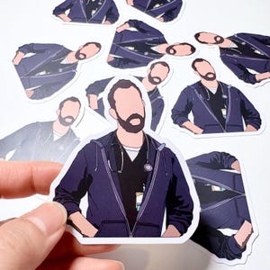 May include: A collection of stickers depicting a faceless illustration of a person in a navy blue zip-up jacket, black shirt, and a stethoscope. The stickers have a white border and are on a white surface.