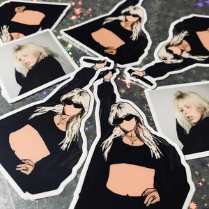 May include: A set of stickers featuring a woman with blonde hair wearing a black crop top and sunglasses. The stickers are printed on white paper with a glossy finish.