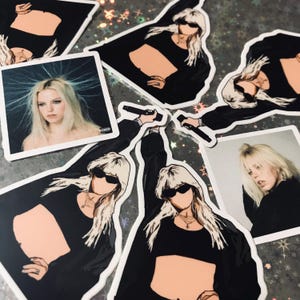 May include: A set of stickers featuring a woman with blonde hair wearing a black crop top and sunglasses. The stickers are printed on white paper and have a glossy finish.