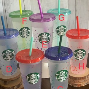 May include: Eight clear plastic tumblers with colorful lids and straws. Each tumbler has a Starbucks logo and a different color confetti pattern. The tumblers are labeled with letters A through H.