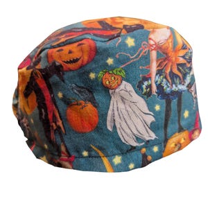 May include: A teal Halloween-themed scrub cap featuring a repeating pattern of jack-o'-lanterns, ghosts, and a woman in a costume. The cap has a curved shape and is made of fabric. Yellow stars and orange accents complete the design.