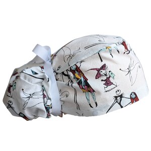 May include: White scrub hat with a tie, featuring a repeating pattern of characters from the Nightmare Before Christmas movie. The characters include Jack Skellington, Sally, and Oogie Boogie.