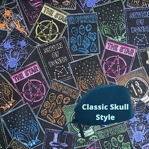 May include: A dark teal scrub cap with ties, featuring the text Classic Skull Style in light blue. The fabric has a repeating pattern of tarot-style cards with illustrations of pentagrams, crystals, spiders, webs, and hands against a black background.