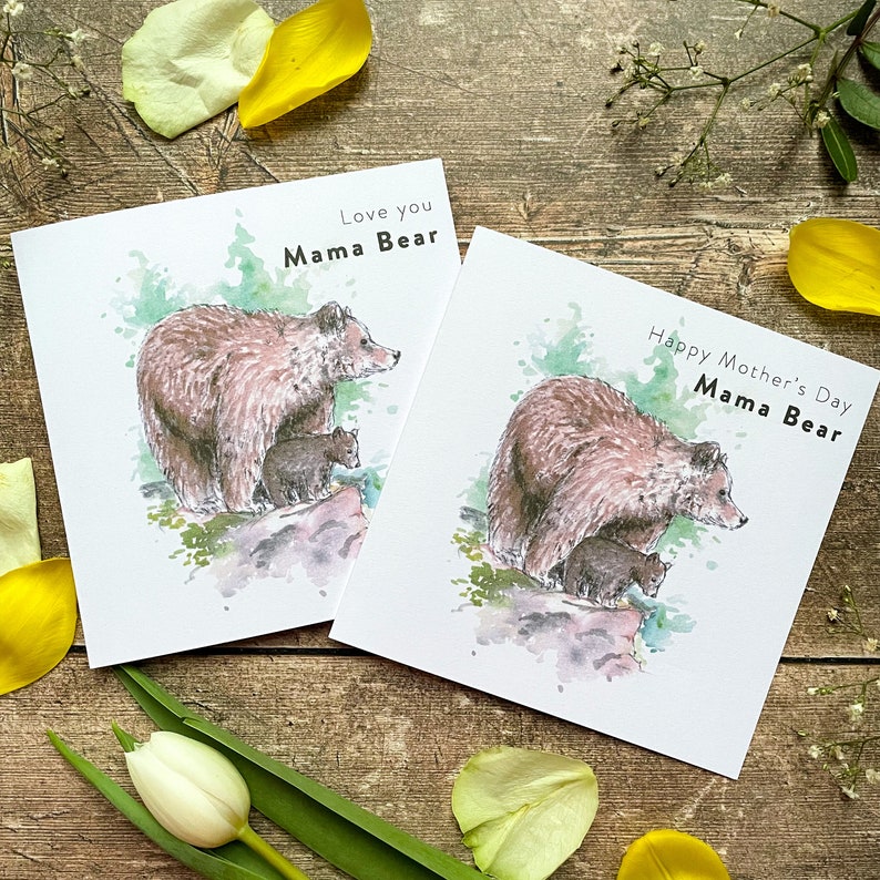 May include: Two watercolor illustrations of a mama bear and her cubs on white greeting cards. The card on the left says "Love you Mama Bear". The card on the right says "Happy Mother's Day Mama Bear".