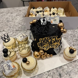 Peut inclure: Un gâteau d'anniversaire noir et doré avec l'inscription "Happy Birthday Bigboy" et plusieurs cupcakes. Les cupcakes et le gâteau sont décorés d'accents dorés, de sphères noires et de faux billets.