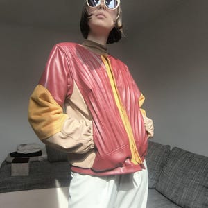 Chaqueta bomber reciclada en rojo, amarillo y marrón, con retazos de piel sintética.
