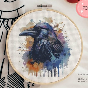 May include: A watercolour-style cross stitch pattern of a raven with blue, purple and orange accents. The pattern is in a 14 count fabric and measures 12.6 inches by 13.8 inches.