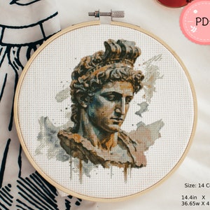 以下が含まれることがあります： 木製の刺繍枠に入ったクロスステッチパターン。青、茶、灰色の水彩画風の陰影が施された古典的なギリシャの彫像の胸像が描かれています。デザインには「PDF, 14 Count, 14.4in x 16.4in, 36.65w x 41.55h cm」というテキストが含まれています。