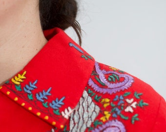 Wool collared jacket with silk lining Small colours embroidered on red - a few small moth bites.