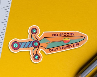 以下が含まれることがあります： 「NO SPOONS ONLY KNIVES LEFT」のテキストが入った剣の形をしたステッカー。ステッカーにはオレンジ、青、緑のアクセントがあります。定規と鉛筆が2本背景にあります。