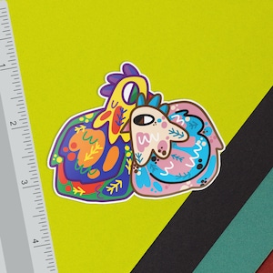 May include: A colorful sticker featuring two cartoon animals, a yellow chicken and a blue and pink creature with a leafy design. The sticker is on a yellow background.