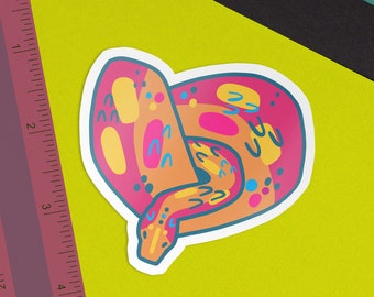 May include: A colorful sticker featuring a stylized illustration of a snake with pink, orange, yellow, and blue patterns.