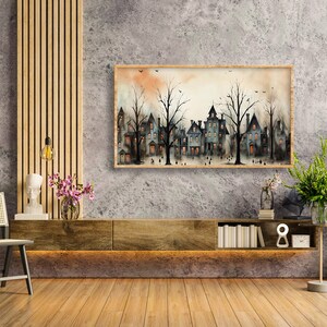 May include: A watercolour painting of a row of houses with trees in front of them. The houses are painted in shades of grey and blue, and the trees are painted in shades of green. The painting is framed in a wooden frame and is hanging on a grey wall.