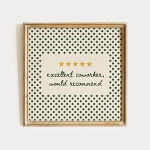 May include: A square framed print featuring a cream-coloured centre with five gold stars and the black cursive text "excellent coworker, would recommend." The border consists of a repeating pattern of small dark green polka dots on a cream background.
