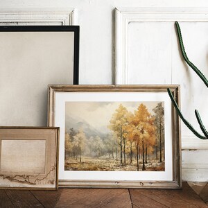 K&ouml;nnte beinhalten: Drei gerahmte Bilder h&auml;ngen an einer wei&szlig;en Wand. Das mittlere Bild ist ein Landschaftsgem&auml;lde eines Waldes mit B&auml;umen in Herbstfarben. Das Bild links ist eine leere Leinwand. Das Bild rechts ist eine leere Leinwand.