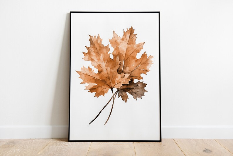 May include: A framed watercolour painting of two brown maple leaves on a white background.