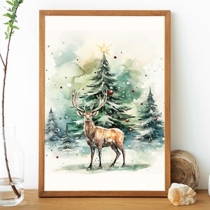 以下が含まれることがあります： 冬の森の風景を描いた水彩画。赤いオーナメントで飾られた常緑樹の前に、大きな角を持つ茶色の鹿が立っています。絵は木製のフレームに入っています。