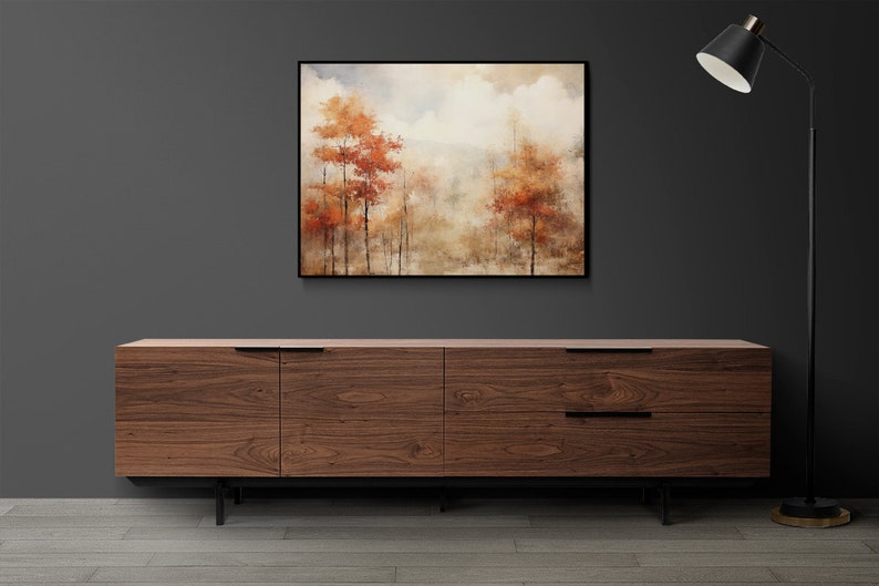 May include: A brown wooden dresser with six drawers and black metal legs. A framed painting of a foggy forest with orange trees hangs above the dresser. A black floor lamp with a black shade stands to the right of the dresser.