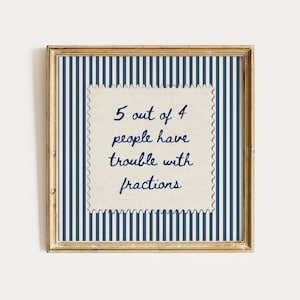 Op de afbeelding: Een vierkante houten lijst met een blauw-witte verticaal gestreepte achtergrond. In het midden bevindt zich een crèmekleurig vierkant met geschulpte randen en de donkerblauwe tekst: 5 out of 4 people have trouble with fractions, in cursief schrift.