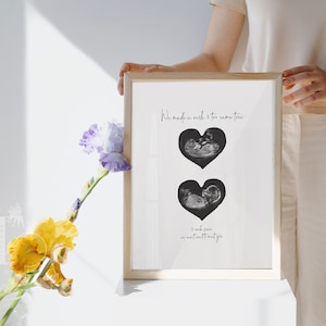 Puede incluir: Una impresión enmarcada con dos imágenes de ultrasonido en blanco y negro en forma de corazón. El texto dice "We made a wish & then came you. We can't wait to meet you."