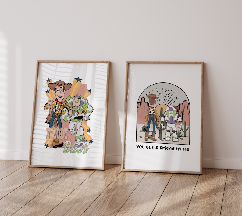 May include: Two framed prints featuring illustrations of Woody and Buzz Lightyear from the Toy Story franchise. The first print shows Woody and Buzz standing together with the text "Woody Buzz" below them. The second print shows Woody and Buzz standing in a desert landscape with the text "You got a friend in me" below them.
