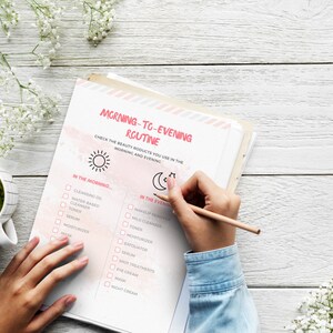 May include: A checklist on a white sheet of paper with a pink watercolor background. The checklist is titled "Morning-to-Evening Routine" and includes a list of beauty products to use in the morning and evening. The checklist is divided into two sections: "In the Morning..." and "In the Evening..." The checklist includes items such as cleansing oil, water-based cleanser, toner, serum, moisturizer, mask, and night cream.