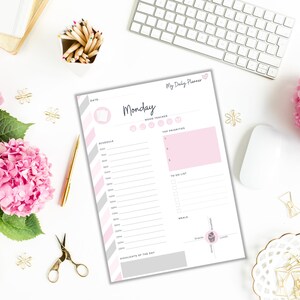 May include: A printable daily planner with a pink and gray color scheme. The planner includes sections for scheduling, mood tracking, top priorities, a to-do list, meals, and highlights of the day. The text "My Daily Planner" is at the top of the page, and the day of the week "Monday" is in a large font.