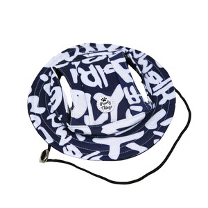 May include: A blue and white dog hat with a black strap and a small white circle with the text "Pawly Things" and a paw print.