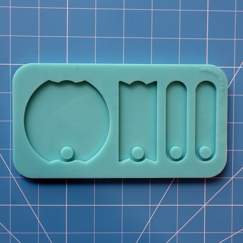 May include: A light blue silicone mold with four shapes: a circle, a banner, and two rectangles. The mold is labeled "MODERN MOLD".