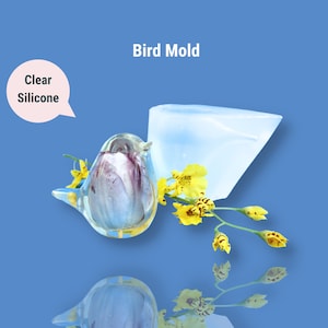 May include: Clear silicone bird mold with a bird shape and a rectangular block. The mold is on a blue background with yellow flowers.