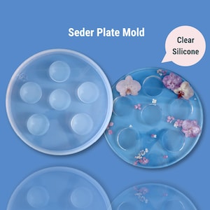 May include: Clear silicone mold for making a Seder plate. The mold has seven round indentations for the traditional Seder plate items. The mold is shown next to a finished Seder plate with dried flowers.