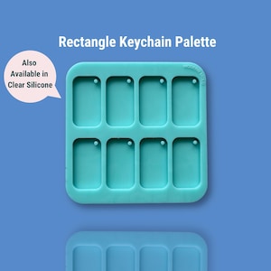 May include: Teal silicone mould with nine rectangular slots for making keychain pendants. Each slot has a small hole at the top. The mould is labelled "Modern Made".