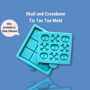 May include: A blue silicone mold for making tic-tac-toe game pieces. The mold has nine squares for the game board and nine squares with skull and crossbones designs.