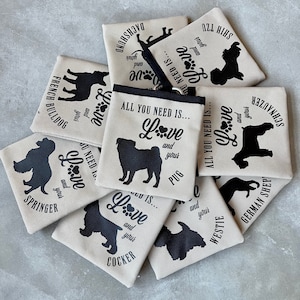 May include: A collection of beige canvas pouches with black dog silhouettes and the text "All you need is... Love and your [breed name]" printed on each pouch. The breeds include Springer Spaniel, Cocker Spaniel, Pug, Westie, German Shepherd, Schnauzer, Shih Tzu, and French Bulldog.