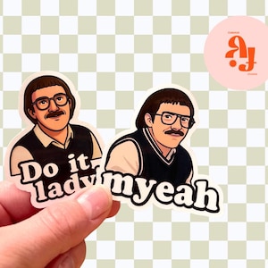 May include: Two stickers featuring a cartoon illustration of a man with glasses and a mustache. One sticker says "Do it lady" and the other says "myeah". The stickers are held by a hand.