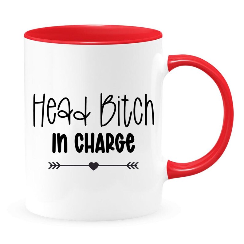May include: White ceramic coffee mug with a red rim and handle. The mug has black text that reads "Head Bitch in Charge" with a small black heart and arrows on either side.