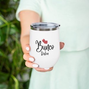 Puede incluir: Un vaso de acero inoxidable blanco con un dise&ntilde;o en negro y rojo que dice "Bunco Babe".