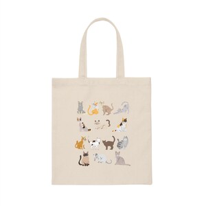 May include: A beige tote bag with a design of various cats in different poses and colors. The cats are arranged in a grid pattern on the bag.